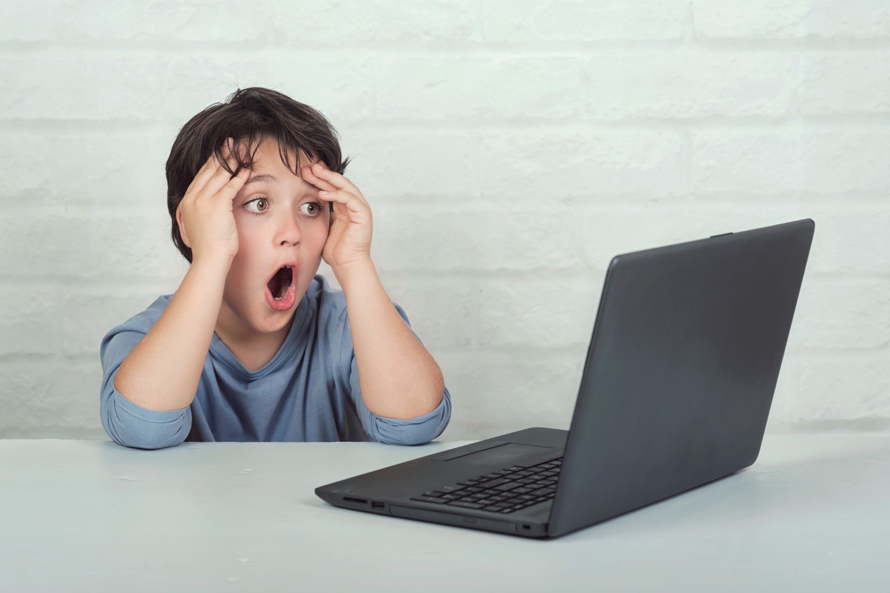 Surprised child reacting to content on a laptop